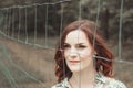 Beautiful redhead girl behind fence outdoors. Royalty Free Stock Photo