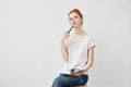 Beautiful redhead girl making notes thinking sitting over white background. Royalty Free Stock Photo