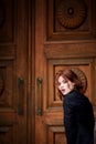 Beautiful redhead girl with plump lips on a background of textured brown door. In a dark suit. Sensual. Ginger