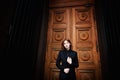 Beautiful redhead girl with plump lips on a background of textured brown door. In a dark suit. Sensual. Ginger