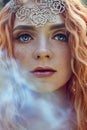 Beautiful redhead Norwegian girl with big eyes and freckles on face in the forest. Portrait of redhead woman closeup in nature Royalty Free Stock Photo