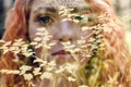 Beautiful redhead Norwegian girl with big eyes and freckles on face in the forest. Portrait of redhead woman closeup in nature