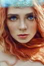 Beautiful redhead Norwegian girl with big eyes and freckles on face in the forest. Portrait of redhead woman closeup in nature Royalty Free Stock Photo