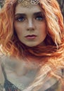 Beautiful redhead Norwegian girl with big eyes and freckles on face in the forest. Portrait of redhead woman closeup in nature