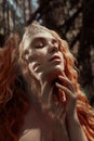 Beautiful redhead Norwegian girl with big eyes and freckles on face in the forest. Portrait of redhead woman closeup in nature Royalty Free Stock Photo