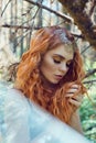 Beautiful redhead Norwegian girl with big eyes and freckles on face in the forest. Portrait of redhead woman closeup in nature Royalty Free Stock Photo