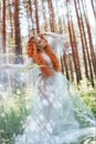 Beautiful redhead woman forest nymph in a blue transparent light dress in the woods spinning in dance. Red hair girls. Art fashion Royalty Free Stock Photo