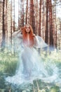 Beautiful redhead woman forest nymph in a blue transparent light dress in the woods spinning in dance. Red hair girls. Art fashion Royalty Free Stock Photo