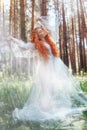 Beautiful redhead woman forest nymph in a blue transparent light dress in the woods spinning in dance. Red hair girls. Art fashion Royalty Free Stock Photo