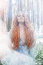 Beautiful redhead woman forest nymph in a blue transparent light dress in the woods spinning in dance. Red hair girls. Art fashion Royalty Free Stock Photo