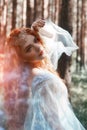 Beautiful redhead woman forest nymph in a blue transparent light dress in the woods spinning in dance. Red hair girls. Art fashion Royalty Free Stock Photo