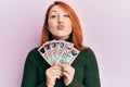 Beautiful redhead woman holding 100 new zealand dollars banknote looking at the camera blowing a kiss being lovely and sexy Royalty Free Stock Photo