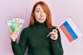 Beautiful redhead woman holding russian ruble banknotes and russia flag depressed and worry for distress, crying angry and afraid Royalty Free Stock Photo