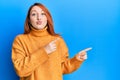 Beautiful redhead woman pointing fingers to the side looking at the camera blowing a kiss being lovely and sexy Royalty Free Stock Photo