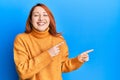 Beautiful redhead woman pointing fingers to the side smiling and laughing hard out loud because funny crazy joke Royalty Free Stock Photo