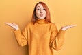 Beautiful redhead woman presenting with open palm looking at the camera blowing a kiss being lovely and sexy Royalty Free Stock Photo