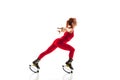 Beautiful redhead woman in a red sportswear jumping in a kangoo jumps shoes isolated on white studio background. Royalty Free Stock Photo