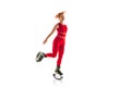 Beautiful redhead woman in a red sportswear jumping in a kangoo jumps shoes isolated on white studio background. Royalty Free Stock Photo