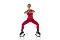 Beautiful redhead woman in a red sportswear jumping in a kangoo jumps shoes isolated on white studio background. Royalty Free Stock Photo