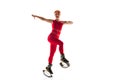 Beautiful redhead woman in a red sportswear jumping in a kangoo jumps shoes isolated on white studio background. Royalty Free Stock Photo