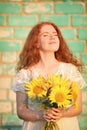 Beautiful redhead woman with sunflowers against brick wall Royalty Free Stock Photo