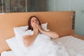 Beautiful redhead Woman waking up in the morning sitting in bed yawning. Good morning. Millennial Caucasian girl wake up Royalty Free Stock Photo