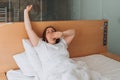 Beautiful redhead Woman waking up in the morning sitting in bed yawning. Good morning. Millennial Caucasian girl wake up Royalty Free Stock Photo