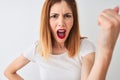 Beautiful redhead woman wearing casual t-shirt standing over isolated white background annoyed and frustrated shouting with anger, Royalty Free Stock Photo