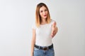 Beautiful redhead woman wearing casual t-shirt standing over isolated white background smiling friendly offering handshake as Royalty Free Stock Photo