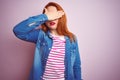 Beautiful redhead woman wearing denim shirt and striped t-shirt over isolated pink background covering eyes with hand, looking Royalty Free Stock Photo