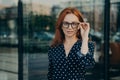 Beautiful redhead woman poses near office building against blurred background Royalty Free Stock Photo