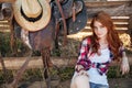 Beautiful redhead young woman cowgirl sitting outdoors