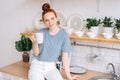 Beautiful redhead young woman holding cup of hot coffee while standing in kitchen room. Royalty Free Stock Photo