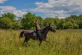 Beautiful redheaded girl riding a horse in countryside. Teen girl rides on the field with grass on a Sunny summer day Royalty Free Stock Photo