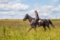 Beautiful redheaded girl riding a horse in countryside. Teen girl rides on the field with grass on a Sunny summer day Royalty Free Stock Photo