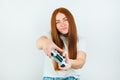 Beautiful redheaded young women looks selfconfident standing on white backgroung playing online exciting game with