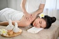 Beautiful and relaxed Asian female receiving massage, lying on massage table in Thai spa salon Royalty Free Stock Photo