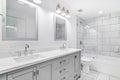A beautiful remodeled bathroom with grey cabinet and white counter top.