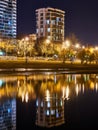 A beautiful residential business class apartment building is reflected at night in the water of the Kuban River bay. The embankmen