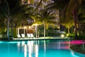 Resort hotel pool at night with lights and palm trees i Royalty Free Stock Photo