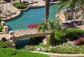 beautiful resort swimming pool with sun chairs, bridge and flowe