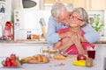 Beautiful retired senior couple having breakfast at home, starting morning with a kiss. Hot cappuccino croissant on the table Royalty Free Stock Photo