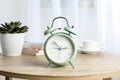 Beautiful retro alarm clock with cup of coffee, succulent plant and books on table Royalty Free Stock Photo