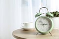 Beautiful retro alarm clock with cup of coffee and succulent plant on table Royalty Free Stock Photo