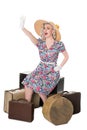 Beautiful retro blond wearing sun hat, seated with vintage suitcases, isolated on white