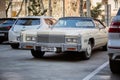 Beautiful retro car Cadillac of beige color in the parking lot in the city near other modern cars