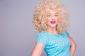Beautiful retro-style blonde girl with voluminous curly hairstyle, in a blue polka-dot blouse on a gray background, smiles and Royalty Free Stock Photo