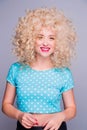 Beautiful retro-style blonde girl with voluminous curly hairstyle, in a blue polka-dot blouse on a gray background, smiles and Royalty Free Stock Photo