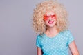 Beautiful retro-style blonde girl with voluminous curly hairstyle, in a blue polka-dot blouse and pink glasses on a gray Royalty Free Stock Photo