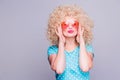 Beautiful retro-style blonde girl with voluminous curly hairstyle, in a blue polka-dot blouse and pink glasses on a gray Royalty Free Stock Photo